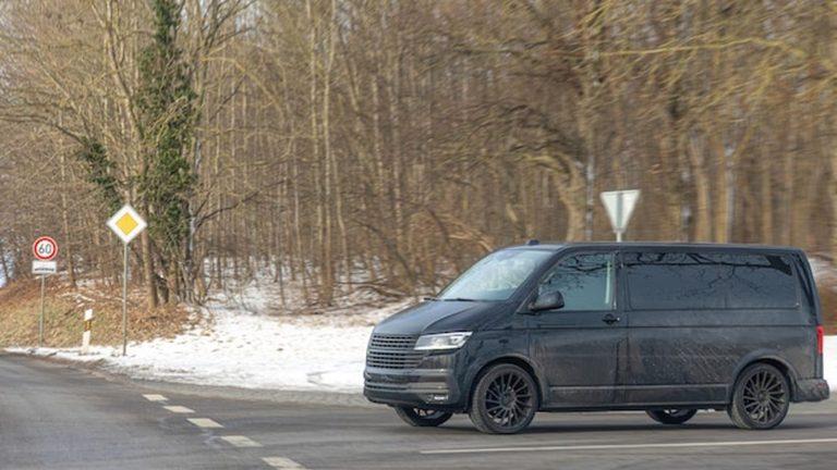 רכב מיניוואן שחור עם נהג בכביש הררי מיוער בטירול